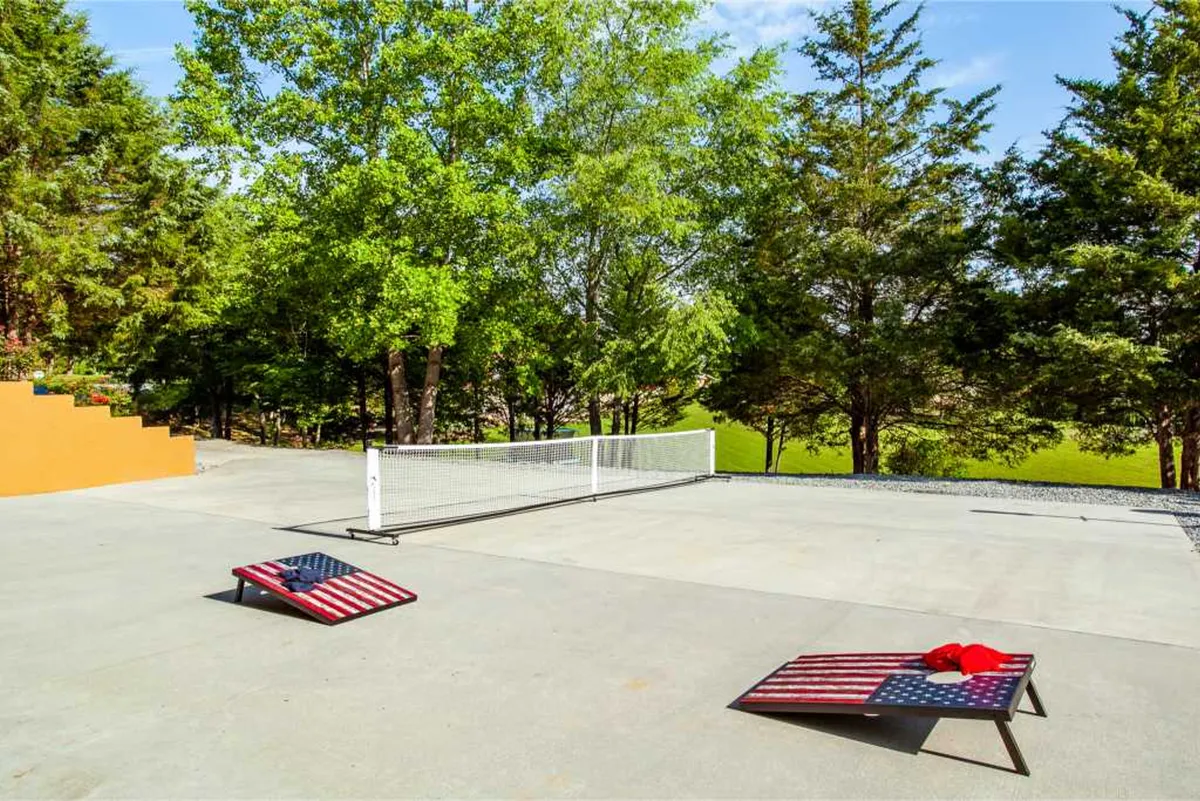 An active scene in the private yard, this image shows cornhole boards and a tennis net surrounded by vibrant greenery. The space is designed for outdoor games, friendly competitions, and relaxed group fun, reflecting the playful side of the property.