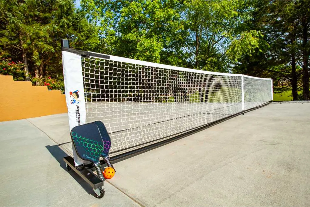 A close-up of a dedicated pickleball court setup, complete with net, paddle, and ball, surrounded by greenery. The setting is energetic and inviting, emphasizing outdoor play and friendly competition.