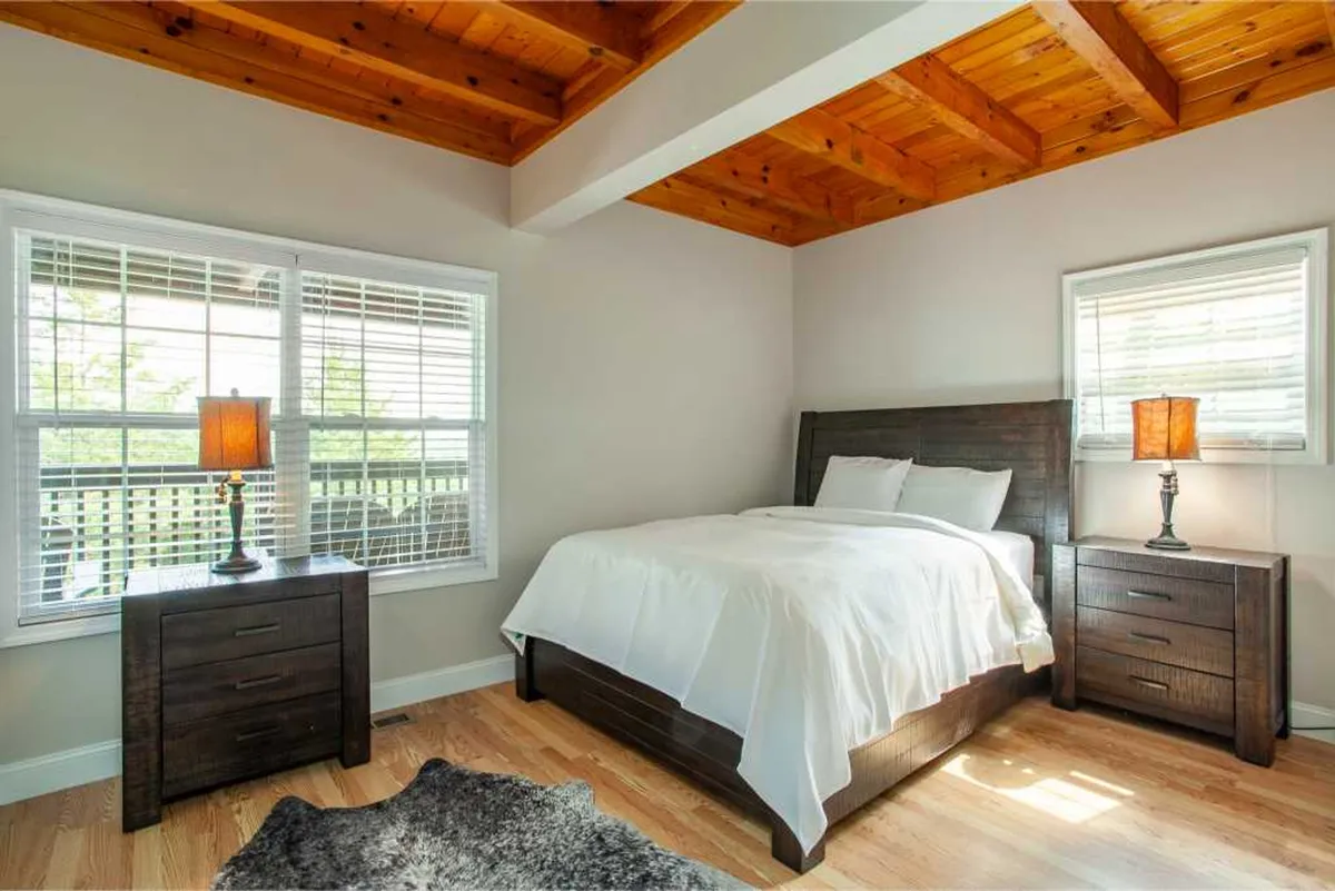 A peaceful bedroom featuring a bed with crisp white bedding, soft lighting from bedside lamps, and a warm wooden ceiling. The space is uncluttered, creating a restful atmosphere ideal for winding down after a day of adventure.